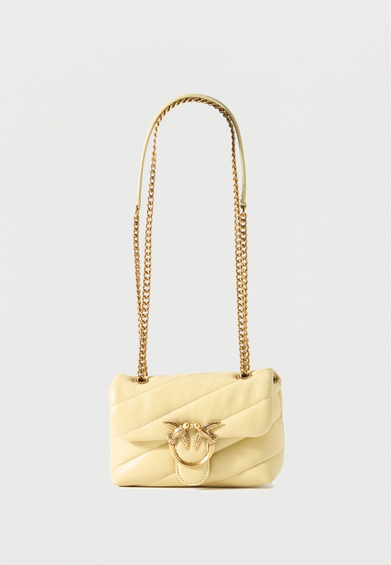 Κίτρινη δερμάτινη τσάντα ώμου με ραφές, χρυσή αλυσίδα λουρί και διακοσμητικό χρυσό κούμπωμα με δύο πουλιά που κοιτάζουν το ένα το άλλο.