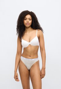 Λευκό σουτιέν με μαλακές θήκες και ρυθμιζόμενους ιμάντες, σετ με ανοιχτό γκρι στρινγκ που διαθέτει λευκή μέση με μπλε λογότυπο της μάρκας.