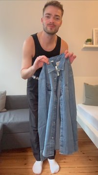 Vestido camisa de denim azul com frente abotoada, colarinho e um único bolso no peito. Apresenta um lavado ligeiramente desbotado e uma bainha desfiada.
