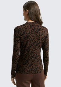 Braunes Langarm-Oberteil mit einem schwarzen Leopardenmuster, ausgestattet mit einem runden Ausschnitt und einem figurbetonten Design. Weicher Stoff.