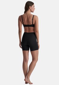 Conjunto de sujetador negro y pantalones cortos de tiro alto. Fabricado con tejido suave, presenta tirantes ajustables y un diseño sin costuras para mayor comodidad.