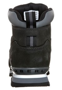 Botte de randonnée en cuir noir avec un design de haute cheville. Présente des accents gris, un embout de talon texturé et une semelle intermédiaire grise marquée.