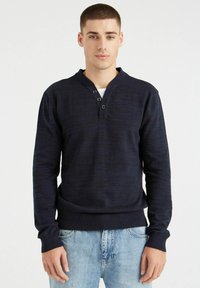 Suéter de punto marino con escote en v y tapeta de tres botones, con puños y dobladillo acanalados. Tejido ligeramente texturizado con un corte relajado.