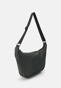 Grøn nylon skuldertaske med en blød tekstur, rund form og justerbar sort rem, der har en lynlås i toppen.