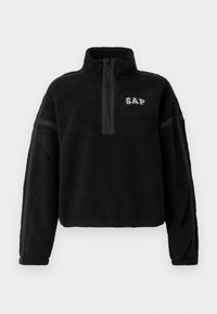 Pullover in pile nero con collo a mezza zip, caratterizzato dal logo GAP. Ha una texture morbida e dettagli bicolore sulle maniche.