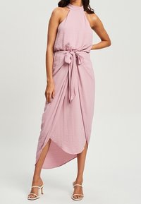 Ärmelloses Kleid mit Halterhals in sanft rosa Stoff mit einer strukturierten Oberfläche. Es hat eine gebundene Taille und einen asymmetrischen Saum mit seitlichen Schlitzen.