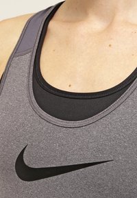 Débardeur sportif en tissu gris chiné avec une couche intérieure noire, encolure dégagée et discret logo Nike noir sur la poitrine.
