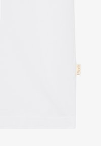 White cotton t-shirt featuring short sleeves, a smooth texture, and a small beige brand tag on the hem.