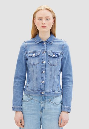 Veste en denim bleu au design ajusté, fermeture à boutons, deux poches poitrine et manches longues. Détails de couture distinctifs partout.