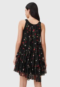 Schwarzes Blumenmusterkleid mit gestuften Rüschen. Verfügt über ein ärmelloses Design, lebendige Blumenmuster in Rot- und Cremetönen. Leichtes, fließendes Material.