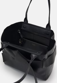 Svart läder tote-väska med en texturerad yta, öppen insida, dubbla handtag, innerfickor och magnetisk knäppning.