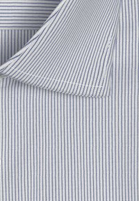 Blauw-wit gestreepte stof met een gestructureerde weving. Bevat een kraag met ronde randen en nauwkeurige stiksels langs de naden.