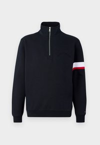 Černý pulovr s dlouhými rukávy a čtvrtzipovým límcem, červený a bílý pruh na pravém rukávu a decentní logo "Hilfiger" na hrudi.