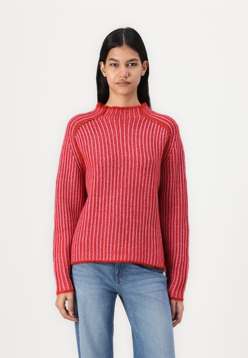 Rød og rosa stripet genser med høy hals, ribbestruktur og lange ermer. Stoffet ser mykt og koselig ut.