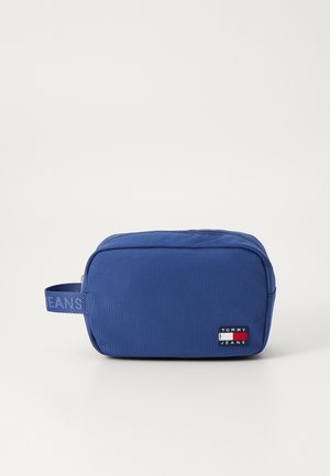 Neceser rectangular azul con superficie texturizada, cuenta con un asa lateral y un parche de logo de Tommy Jeans. Cierre de cremallera en la parte superior.