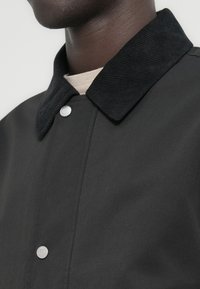 Μαύρο σακάκι με γιακά από κοτλέ και κουμπιά με πατιλέτα. Διαθέτει ομαλή υφή υφάσματος και κομψό σχέδιο στη γραμμή του λαιμού.