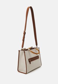 Sac à main beige avec des bordures marron, en tissu texturé, avec une poignée supérieure dotée d'accents en bambou et une sangle en cuir amovible. Comprend une poche zippée.