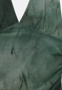 Green fabric with a soft, slightly textured surface. Features a deep V neckline and gathered fabric details along the edges.