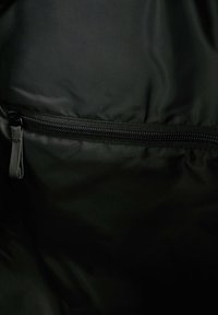 Interior de bolsa de nylon negra con textura suave, que cuenta con un bolsillo con cremallera a lo largo del borde superior para un almacenamiento seguro.