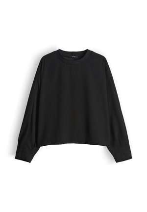 Blouse noire courte en tissu doux, avec un col rond et de longues manches amples ornées d'une discrète couture sur le devant.