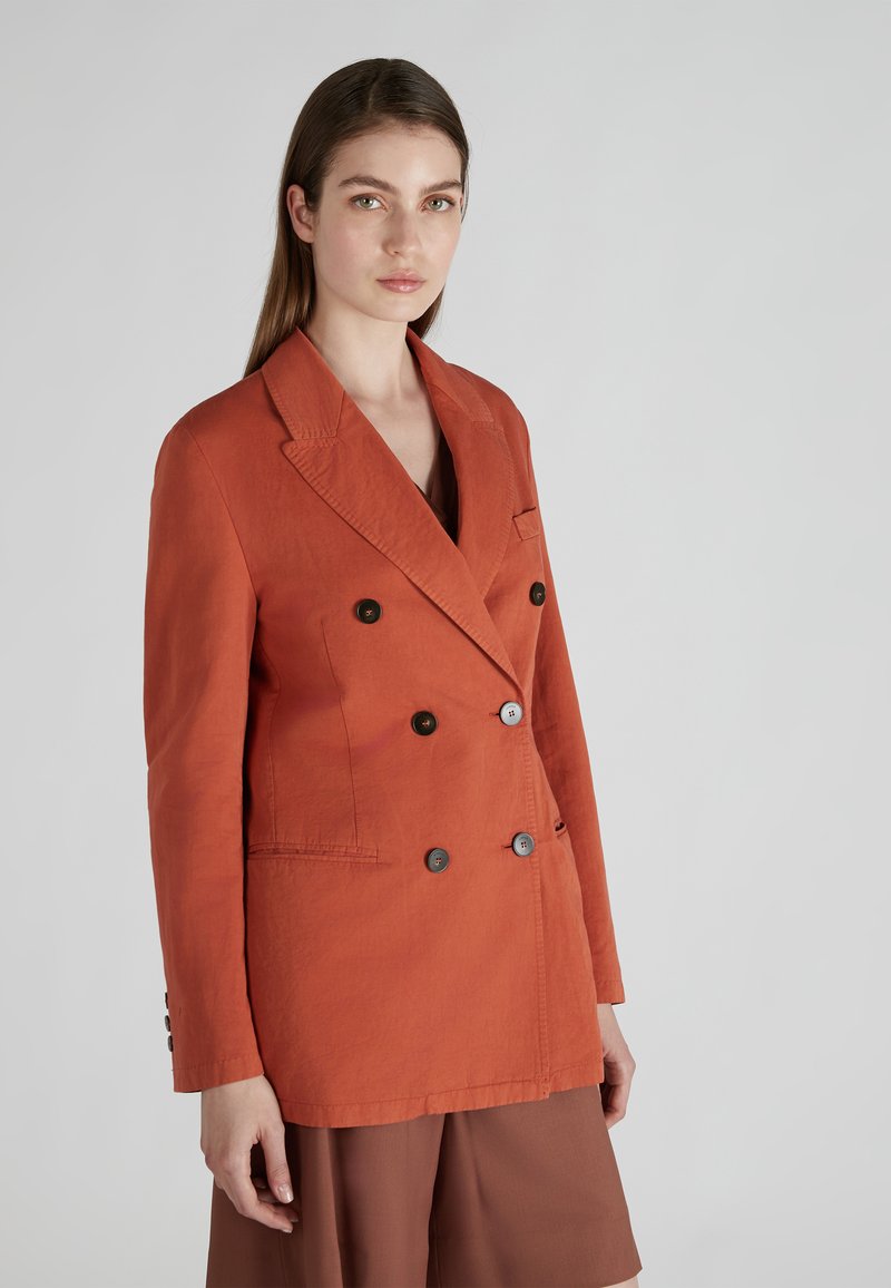 Blazer de doble botonadura en tela de color naranja oxidado con solapas de muesca, tres bolsillos decorativos y botones marrones; acabado texturizado.