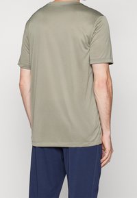Camiseta de manga corta verde oliva hecha de tela suave, con cuello redondo y ajuste relajado, vista desde la parte de atrás.