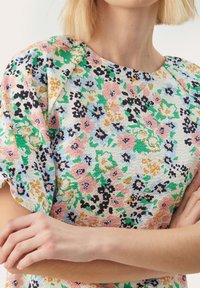 Bloemenpatroon jurk met levendige kleuren: roze, blauw, groen en zwart. Gestructureerde stof met korte mouwen en een ronde hals.