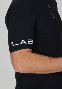 Schwarzes Radtrikot aus glattem, dehnbarem Material; mit figurbetontem Schnitt, kurzen Ärmeln und großem weißen "ELITE LAB"-Logo auf dem Arm.