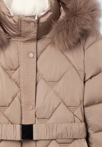 Giacca imbottita beige con trapuntatura a diamante, bordo della cappuccio in pelliccia sintetica, chiusura a scatto e cintura in tessuto con dettaglio della fibbia metallica.