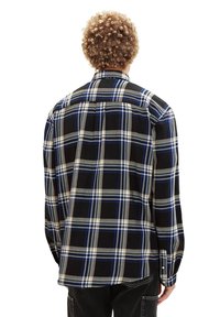 Schwarzes und blaues kariertes Flanellhemd mit langen Ärmeln, einem Button-Down-Kragen und Rückenschlitzdetails. Sanfte Textur und lockere Passform.
