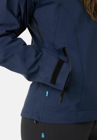 Navy waterproof jacket with a smooth texture, featuring black zipper pockets, Velcro cuffs, and small Swedish flags as accents.