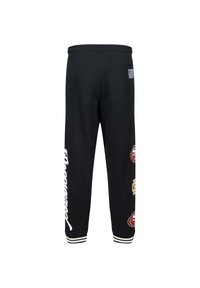 Zwarte joggingsbroek met een trekkoord in de taille, witte tekst en geborduurde logo patches in rood en goud op de onderbenen. Witte gestreepte boorden.
