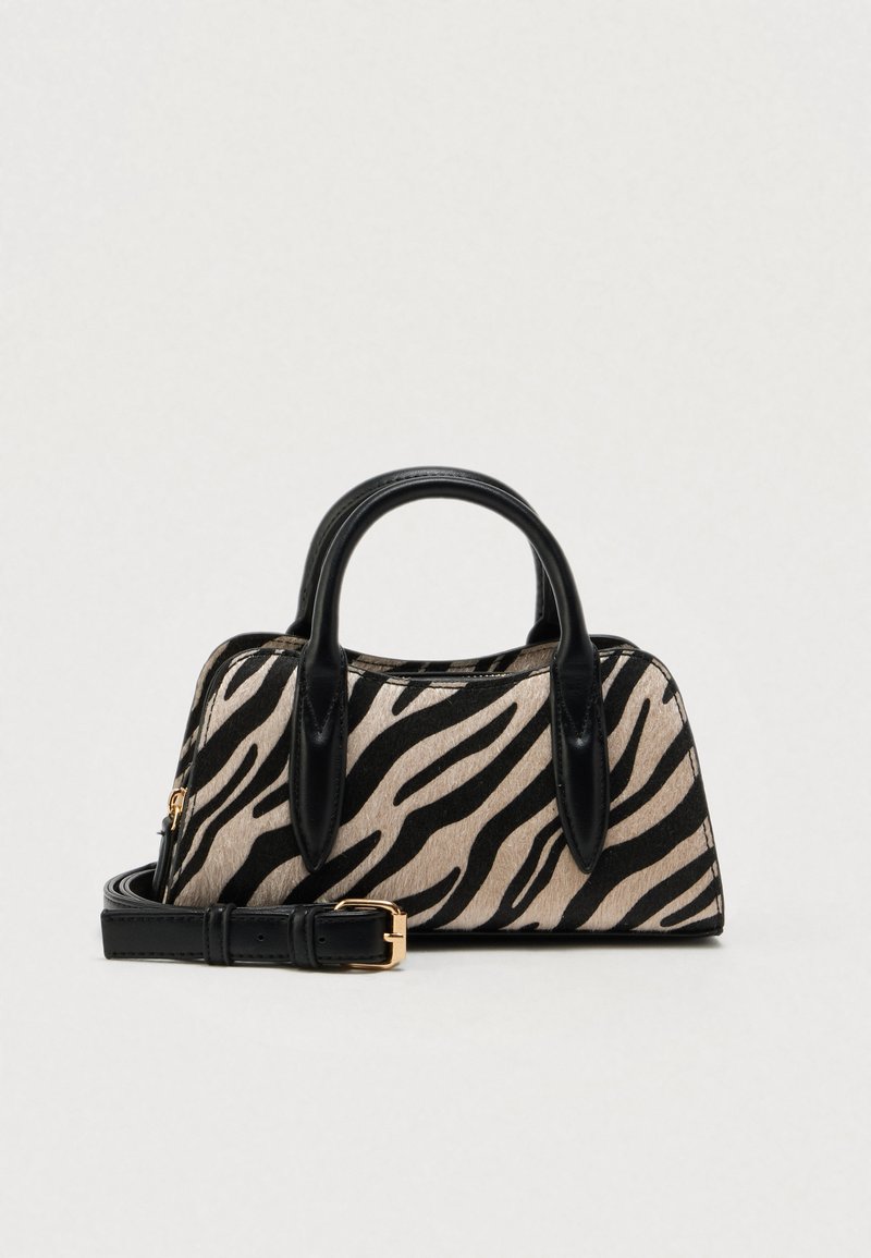 Sac à main imprimé zèbre noir et beige avec un design structuré, des poignées en cuir et une bandoulière amovible. Accent de ferrures dorées.