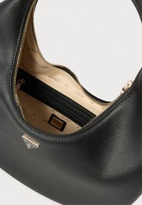 Mustast tekstureeritud sünteetilisest materjalist käekott, millel on kuldne tõmblukk, kontrastne beež vooder korduva logomustriga ning sisemine tasku.