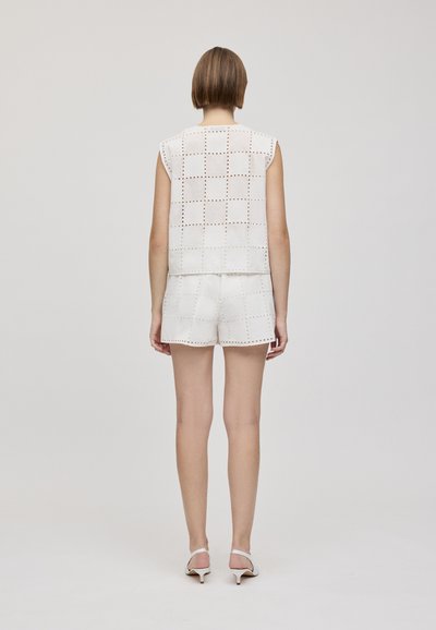White sleeveless top and shorts set featuring a grid pattern with cutouts. Smooth texture, minimal design, and subtle stitching details.
