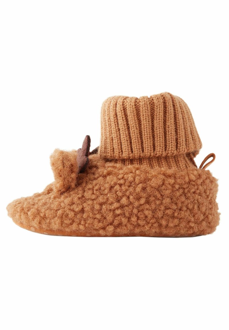 Tan ulltofflor med en texturerad, fluffig yta, ribbad stickad krage och en dekorativ bladdetalj. Mjuk, varm och mysig design.