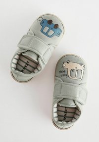 Grau gewebte Schuhe mit Klettverschlüssen, die ein blaues Auto und ein beiges Bärenmotiv auf den Zehen zeigen. Innere Streifen sind sichtbar. Gummisohlen.
