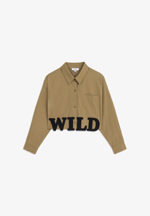 Cropped brown shirt with a collar, button closure, single chest pocket, and prominent black "WILD" lettering at the hem.