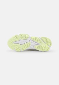 Suela de zapato atlético blanca con un acabado de goma texturizada. Presenta acentos verdes en un diseño ondulado y patrones circulares de agarre.