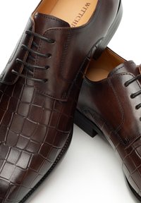 Hnědé kožené boty s krokodýlím vzorem, kulatou špičkou, šněrováním a hladkým povrchem s mírným podpatkem pro zvýšení elegance.