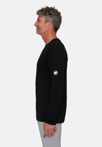 Zwarte lange mouw shirt met een ronde hals, met een wit logo op de linkermouw. De stof lijkt glad en aansluitend.