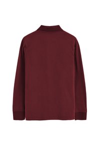 Vinröd långärmad pikétröja sedd bakifrån med ribbstickade muddar och uppvikt krage mot en vit bakgrund.