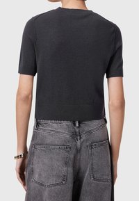 Short-sleeve, dark gray knit top with a cropped design, ribbed cuffs, and hem. Smooth texture. Worn with high-waisted, washed gray jeans.