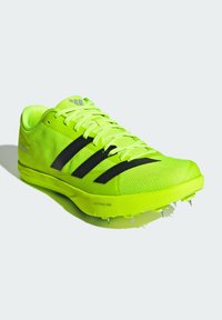 Scarpa sportiva verde lime brillante con strisce nere, tomaia in mesh, design testurizzato e tacchetti suola per la trazione.