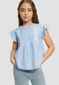 Bluse mit blau-weißen Streifen, mit gewellten Ärmeln, plissierter Textur und floralen Bestickungen auf der Vorderseite.