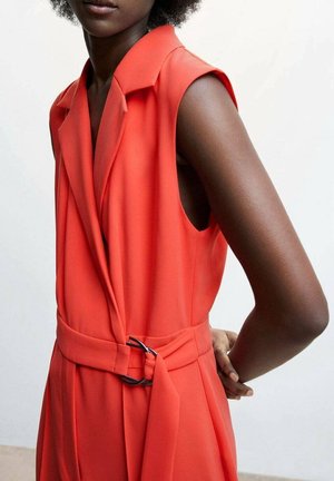 Robe rouge sans manches avec un col à revers, taille cintrée et ceinture en tissu. Le matériau semble lisse avec un léger éclat.