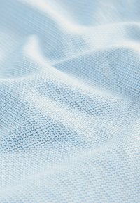Tissu texturé bleu clair avec un motif en grille. Matériau doux et tissé avec une surface lisse, présentant de petites formes géométriques espacées uniformément.