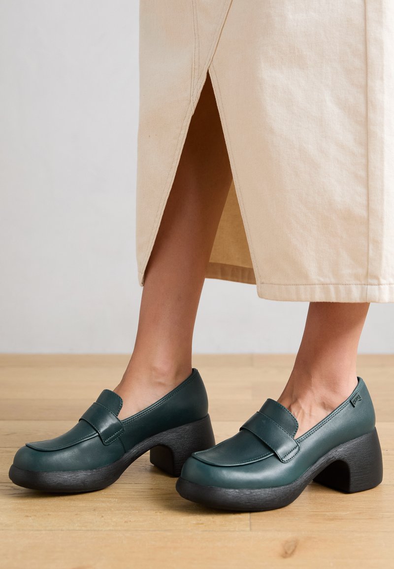 Scarpe in pelle verde con punta rotonda e una larga fascia sul davanti. Tacco chunky nero con superficie texturizzata. Superficie liscia, design a taglio basso.