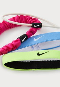 Trys Nike plaukų gumelės rožinės, mėlynos ir žalios spalvos. Medžiagos skiriasi: dvi yra elastingos, o viena - iš audinio. Kiekviena turi juodą Nike logotipą ant išskirtinės juostos.