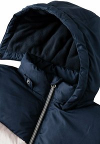Giacca puffer blu navy con cappuccio foderato in pile, zip argentata e bottoni a pressione. Presenta una texture trapuntata e un design con collo alto.